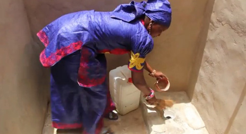Diabou cleans the latrine her husband built for the family.: Photograph©WSSCC/Katherine Anderson